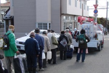 東日本大震災で水の配給を待って並ぶ人々